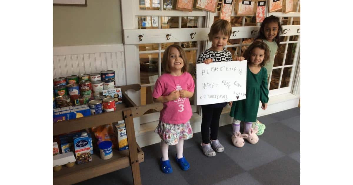 a group of young children holding a handwritten sign asking for help with their food drive and their goal of collecting 200 items
