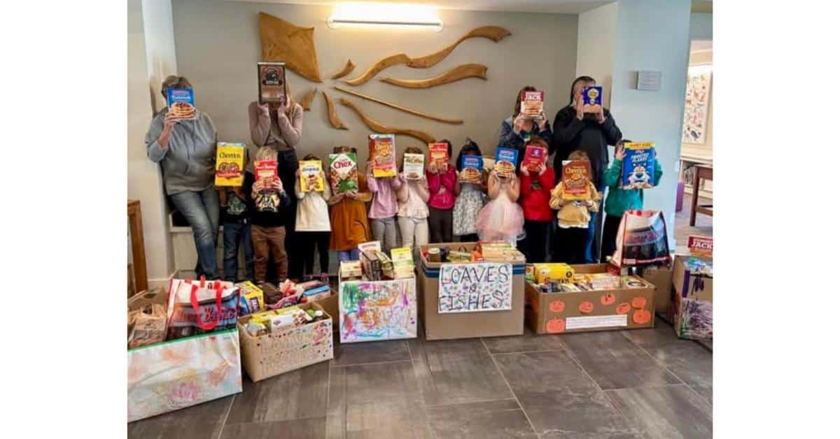 group of students and teachers behind boxes of breakfast food holding cereal boxes in front of their faces