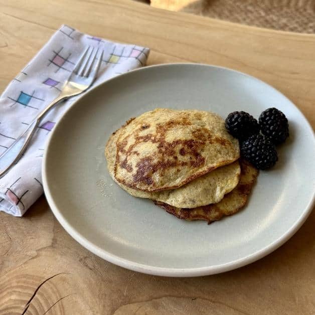banana pancakes on a plate with black berries